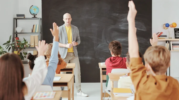 Klassenzimmer einer Schule mit Schülern, Lehrer und einer schwarzen Tafel